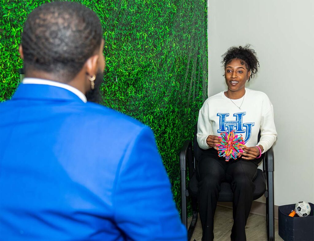 A photo of a student talking with a SCC staff member while holding a colorful fidget toy.