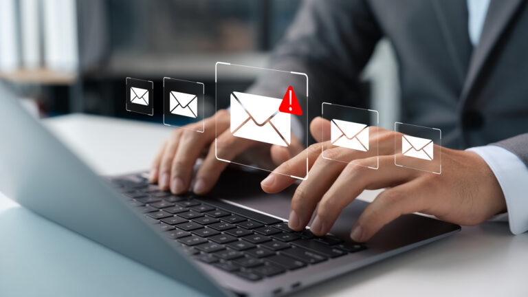 Graphic of a person's hands on a keyboard with a email icon displaying a warning.