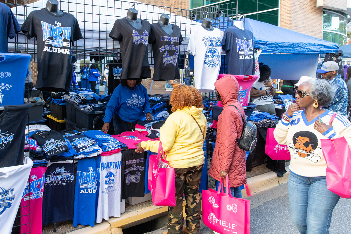 A photo of patrons looking at shirts for sale at a homecoming vendor's table.