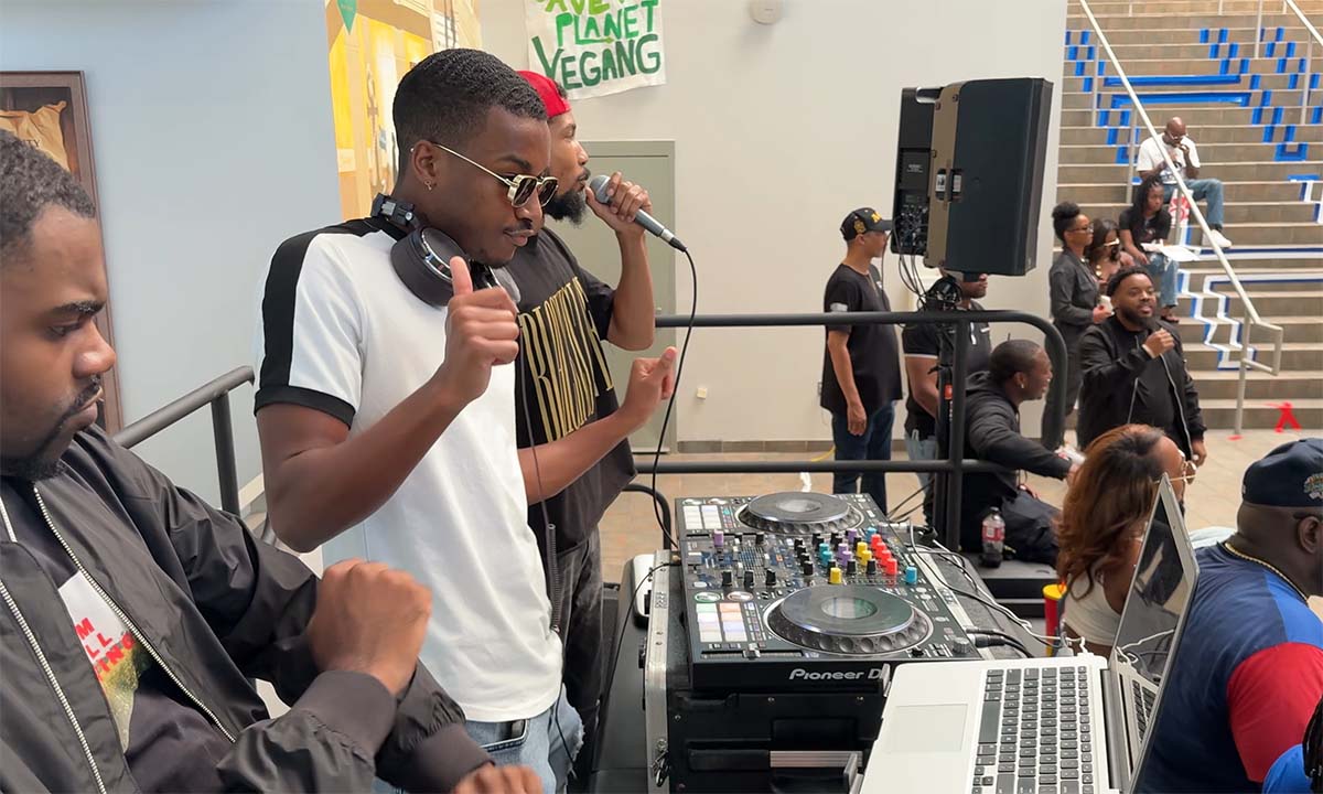 A photo taken of the interior of the HU Student Center. A young man DJ's as attendees look onward and enjoy the music.