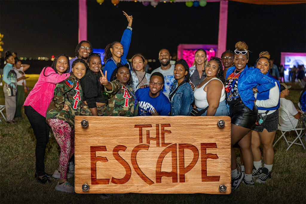 A photo showing smiling HU Alumni with a graphic on top displaying the text "The Escape"