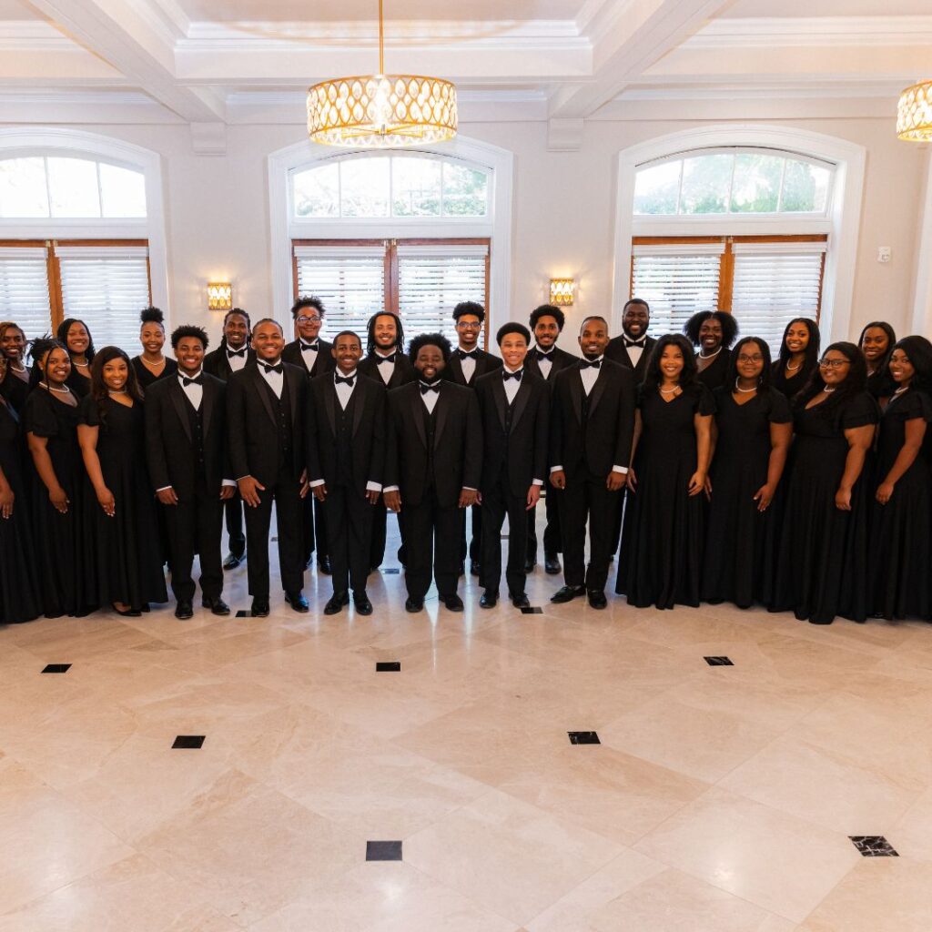 A photo of a group of choir members wearing black dresses and suits.