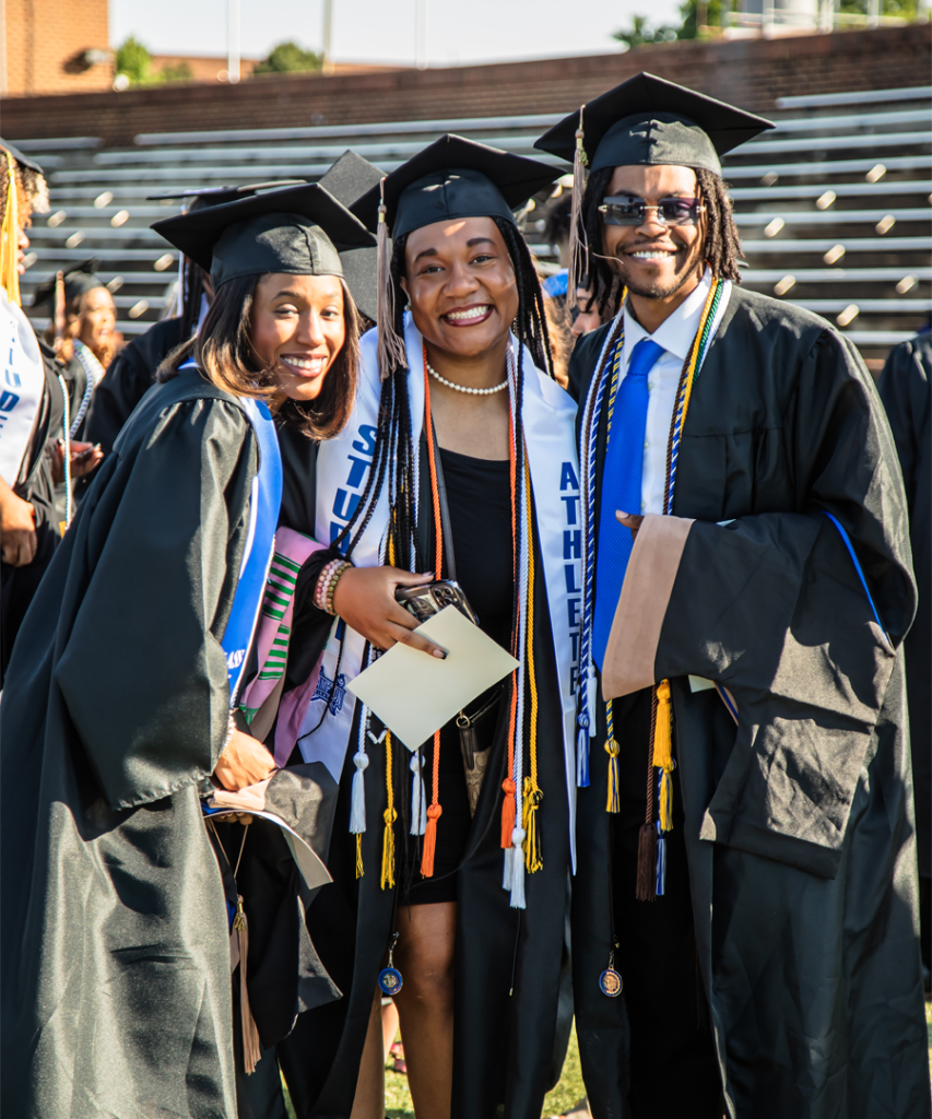 Photo of three students in graduation regalia.