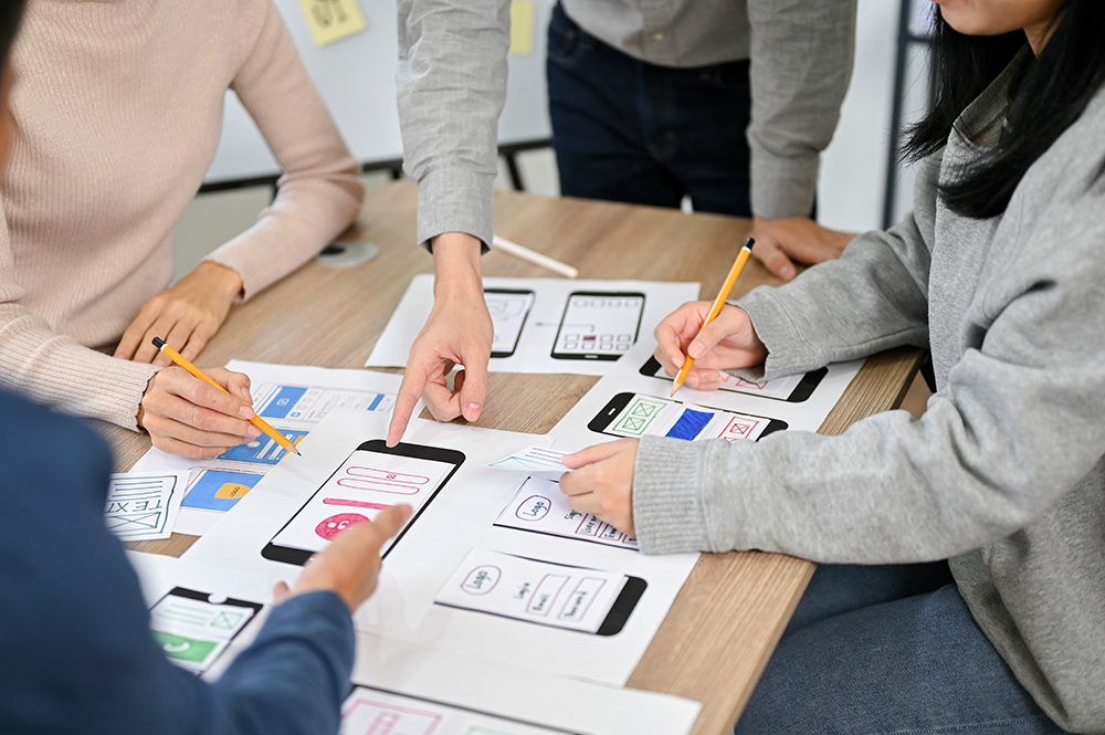 A photo of people collaborating on designs around a table.