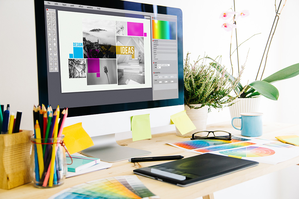 A photo of a graphic design work desk, showing a computer running an image editing software.