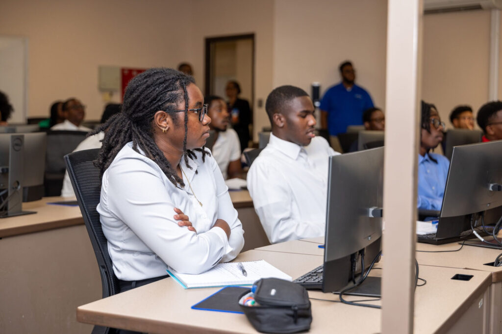 Students sitting at computers listen to a presentation.