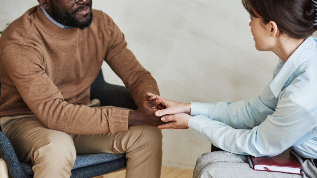 Two people talk to each other while holding hands.