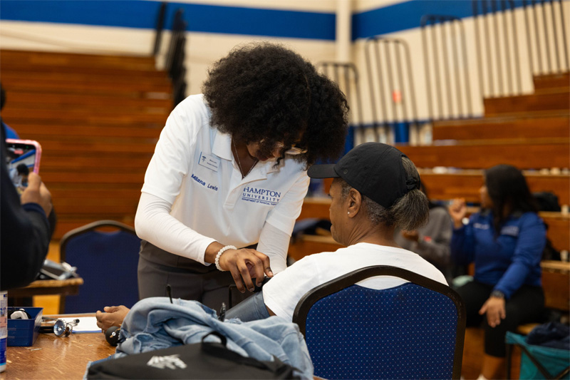 A student clinician takes a blood pressure reading of a senior attendee.