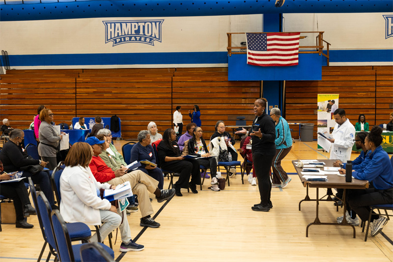 A faculty clinician talks to a crowd of senior attendees.