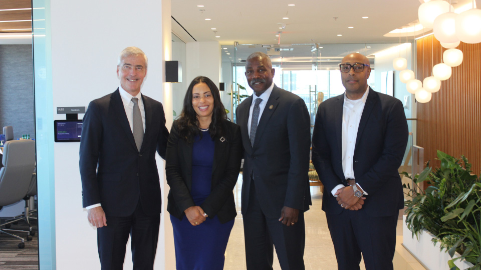 A photo of four people wearing professional attire standing side-by-side.