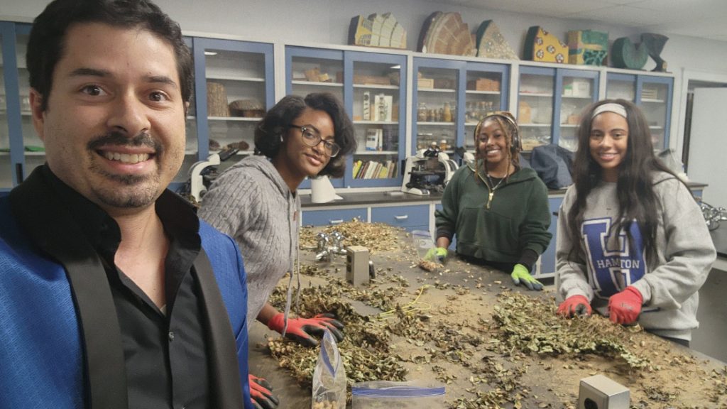 A photo of a professor and students examining dissected plants on a table.