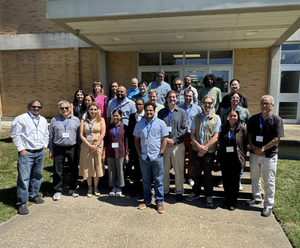 A photo of a group of meeting participants posing for the camera outside on the steps of a building.