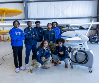 Students posing by a small electric aircraft.