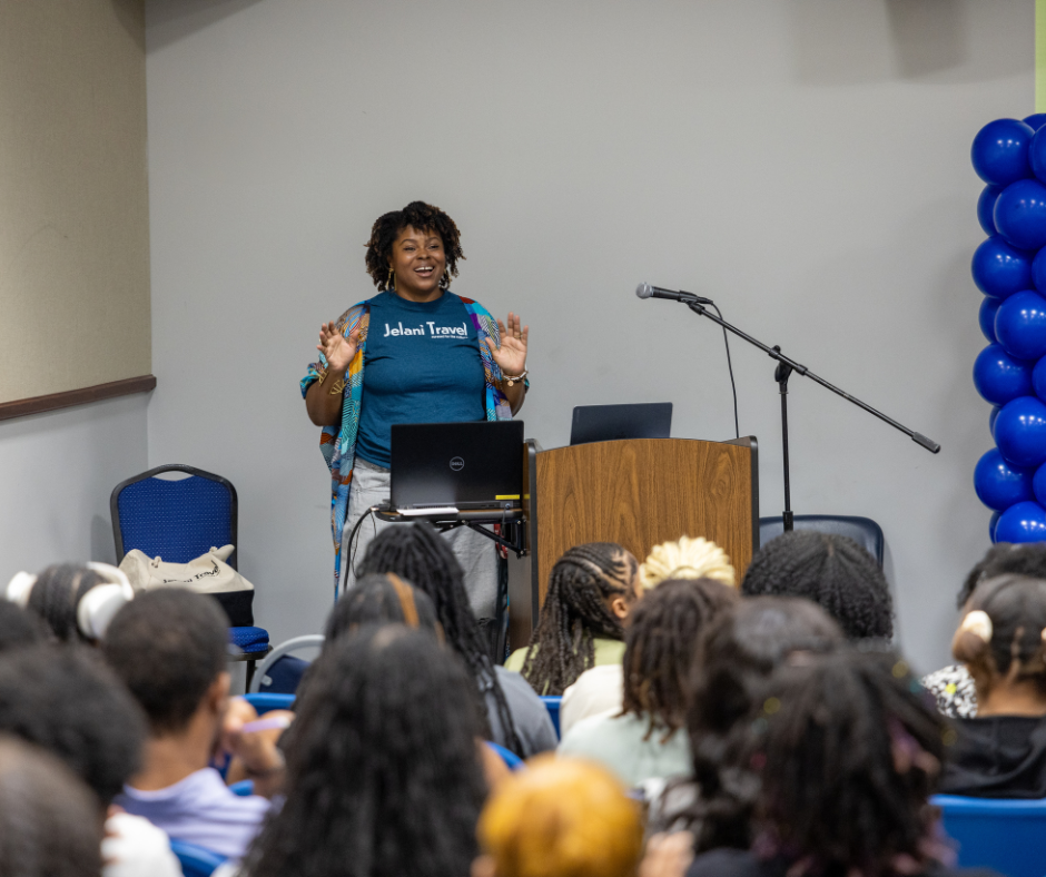 Woman speaking to group of students in theatre.